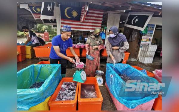 Sauffian (kiri) melayani pelanggan yang berkunjung ke gerainya yang beroperasi di simpang kebun, Kampung Tualang, Manir di Kuala Terengganu.