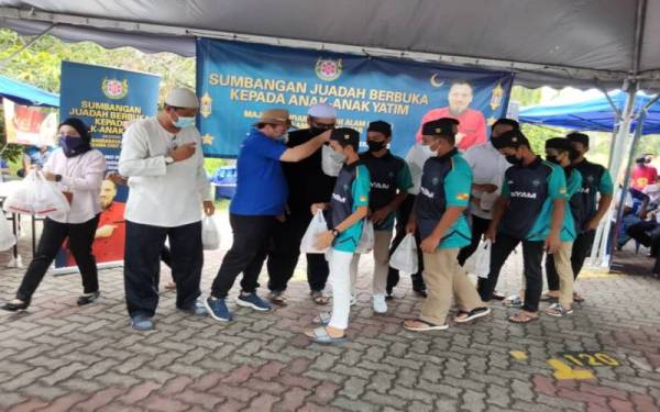 Cef Ammar (tiga, kiri) menyerahkan bungkusan nasi Arab kepada anak yatim sempena program Sumbangan Juadah Berbuka Puasa anjuran bersama MBSA di Bazar Ramadan Seksyen 13, Shah Alam, pada Khamis.