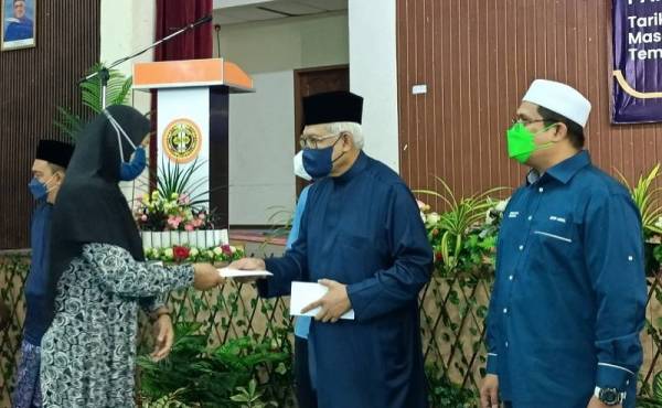 Hamzah (dua dari kanan) menyampaikan bantuan kepada salah seorang penerima yang terjejas akibat ribut sempena Majlis Berbuka Puasa Perikatan Nasional (PN) Larut di Dewan Majlis Daerah Selama pada Jumaat.