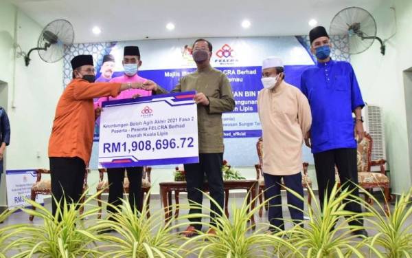 Abdul Rahman (tengah) menyerahkan replika cek Agihan Keuntungan Daerah Kuala Lipis membabitkan nilai RM1,908,696.72.