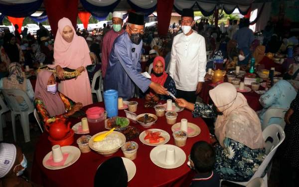 Mahdzir (empat dari kanan) menyampaikan bantuan kepada penerima asnaf miskin ketika Majlis Berbuka Puasa Bersama Warga Kemas dan masyarakat setempat di Pusat Komuniti Padang Kerasak pada Sabtu. - Foto Bernama