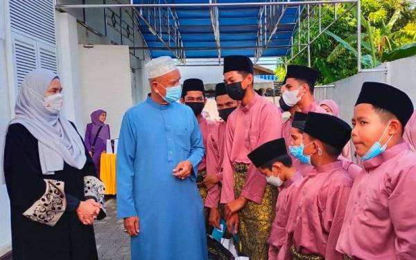 Che Ibrahim (dua dari kiri) menyampaikan sumbangan zakat kepada anak-anak yatim dan golongan asnaf serta miskin di Depo E-Mutiara Panji, Kota Bharu pada Ahad.