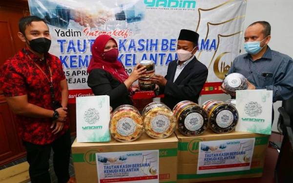 Mahadi (dua dari kanan) menyampaikan biskut raya kepada Majidah (dua dari kiri) mewakili Kemudi di Jabatan Penyiaran Kelantan, Kota Bharu pada Isnin.