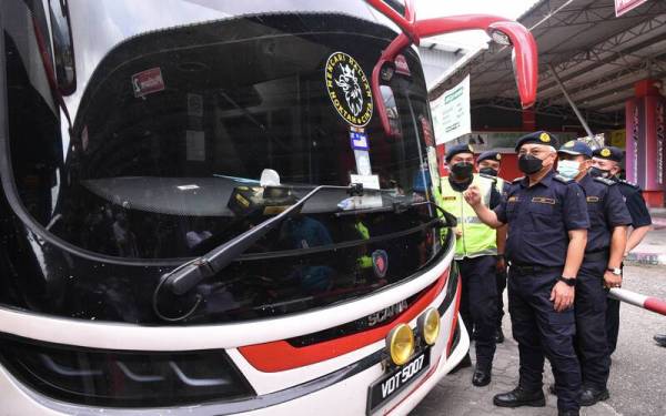 Lokman (tengah) melihat slip pemeriksaan bas oleh JPJ sebelum mengadakan sidang akhbar pemeriksaan depoh bas di Depoh Bas Sani Ekspress, Klang Sentral pada Isnin. - Foto Bernama