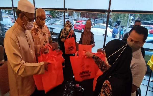 Mahfuz (dua dari kiri) menyerahkan cenderahati kepada pengamal media yang hadir ke Majlis Berbuka Puasa bersama Ahli Kelab Media Elit Kedah (KMEK) petang Isnin.