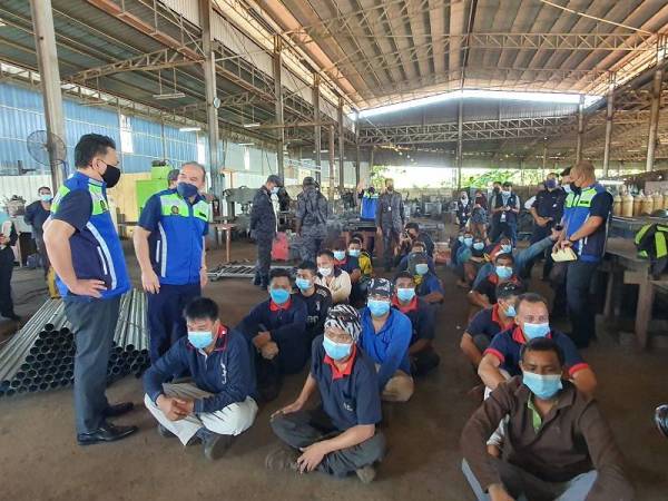 Mohd Asri (dua dari kiri) bertanyakan sesuatu kepada pekerja asing yang diperiksa di sebuah kilang besi dalam operasi pada Rabu.