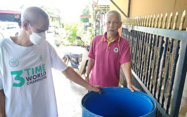 Ab Rahim (kiri) dan Othman menunjukkan tong berisi air hujan yang digunakan bagi tujuan pembersihan berikutan ketiadaan bekalan air di Kampung Sungkap Para.