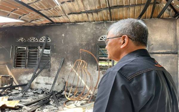 Zainuddin melihat keadaan rumah Nazri yang musnah dalam kebakaran.