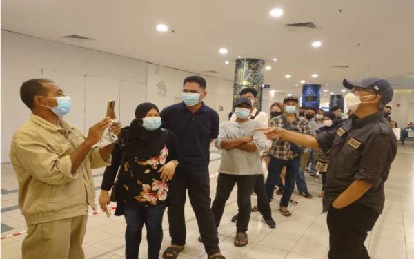 Hermono (kanan) meluangkan masa beramah mesra dengan warga Indonesia yang beratur membeli tiket untuk pulang di Terminal Feri Antarabangsa Stulang Laut, Johor Bahru, pada Khamis.