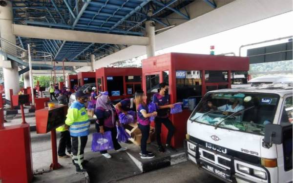 Kakitangan Pusat Pakaian Hari-Hari memberikan 'goodies bag' kepada pengguna Lebuhraya Grand Saga yang melalui Plaza Tol Batu 11, Cheras pada Khamis.