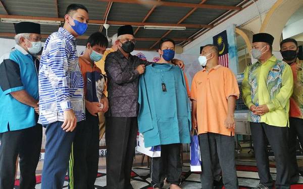 Daud (tiga dari kiri) menyampaikan baju Melayu kepada salah seorang penerima pada program Kembara Ramadan Prihatin dan MAIWP bersama asnaf pada Khamis.