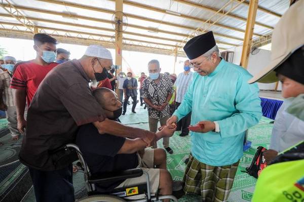 Annuar Musa (kanan) menyampaikan sumbangan zakat kepada golongan Asnaf dalam Parlimen Ketereh 2022 di Kompleks Yayasan Kemiskinan Kelantan (YKK), Melor pada Jumaat. - Foto Bernama