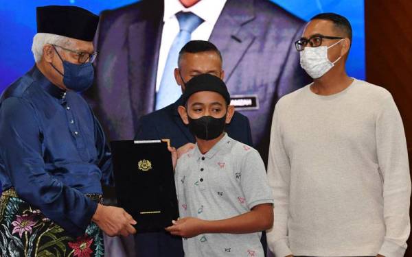 Hamzah (kiri) menyampaikan surat keputusan kewarganegaraan kepada para penerima pada Majlis Penyerahan Surat Keputusan Kewarganegaraan di Kementerian Dalam Negeri hari ini. - Foto Bernama