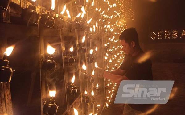 Seorang belia menghidupkan api di gerbang pelita raya di Kampung Baru Sri Gading, Batu Pahat.