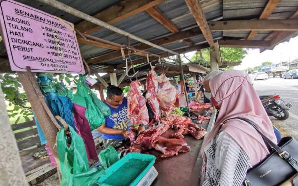 Seorang peniaga melayani pelanggan yang berkunjung ke gerai jualan daging di Manir.