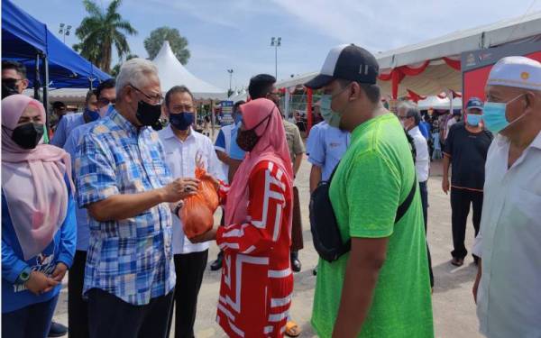 Noh (dua dari kiri) mengagihkan ayam kepada penduduk pada Majlis Perasmian JHP Syawal di Padang Astaka di sini, pada Sabtu.