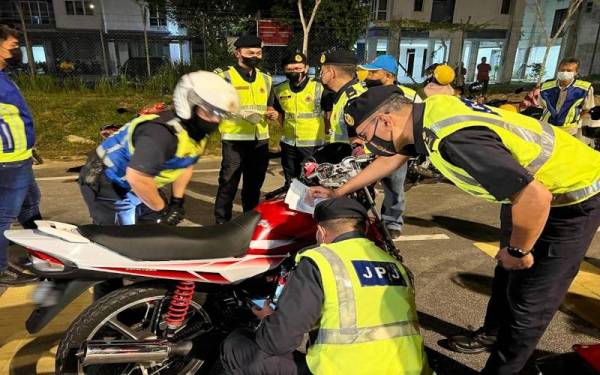 Zulkarnain (kanan) melakukan pemeriksaan ke atas sebuah motosikal pada hari pertama pelaksanaan Op Hari Raya Aidilfitri 2022 (OP HRA 2022) di Gong Badak, Kuala Nerus pada Sabtu malam.