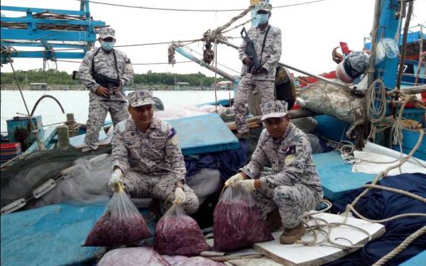 Rashidilhadi (duduk, kiri) menunjukkan sebahagian hasil laut dalam bot nelayan Vietnam yang ditahan pada Isnin. - Foto Maritim