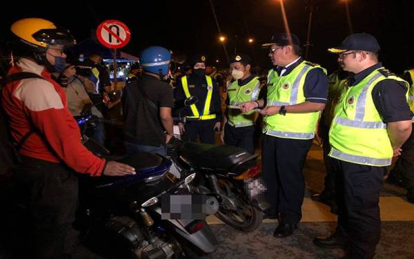 Zailani (dua dari kanan) memeriksa lesen seorang penunggang motosikal di Sekatan Jalan Raya (SJR) di Pasir Pekan, Tumpat.