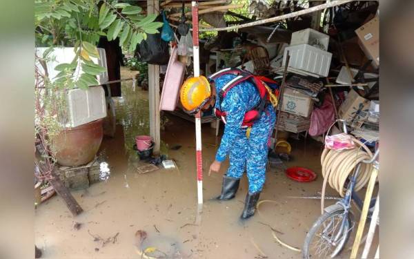 Anggota APM Kubang Pasu memeriksa paras air di kediaman penduduk yang dinaiki air.