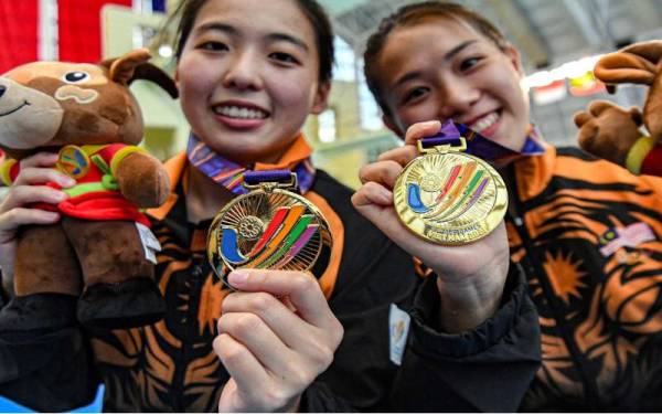 Atlet Terjun Negara, Ng Yan Yee (kanan) dan Ong Ker Ying (kiri) bergambar dengan pingat Emas masing-masing selepas beraksi dalam acara 3M papan anjal seirama wanita sempena Sukan SEA 2021 di Pusat Akuatik My Dinh, pada Isnin. - Foto Bernama 