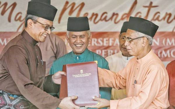 Muhammed (tengah) menyaksikan pertukaran dokumen antara Mohd Ekhwan (kiri) dengan Ketua Pegawai Eksekutif Yayasan Undang Johol, Md Ghazali Md Yasin (kanan) ketika Majlis MoU dan MoA antara UKM dengan Undang Luak Johol pada Rabu.