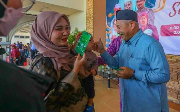 Tuan Ibrahim (kanan) menyampaikan duit raya kepada tetamu pada Majlis Rumah Terbuka Pas Kelantan di Dataran Warisan Stadium Sultan Muhammad IV, Kota Bharu pada Khamis.