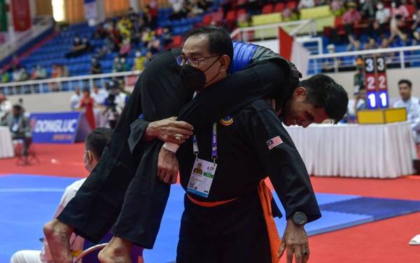 Mazlan mengangkat Al Jufferi yang mengalami kecederaan dan kesakitan pada perlawanan suku akhir Silat Tanding Kategori Lelaki F menentang Iqbal Candra pada Sukan SEA Hanoi 2021 di Gelanggang Silat Pusat Sukan Bac Tu Leim pada Jumaat. - Foto Bernama