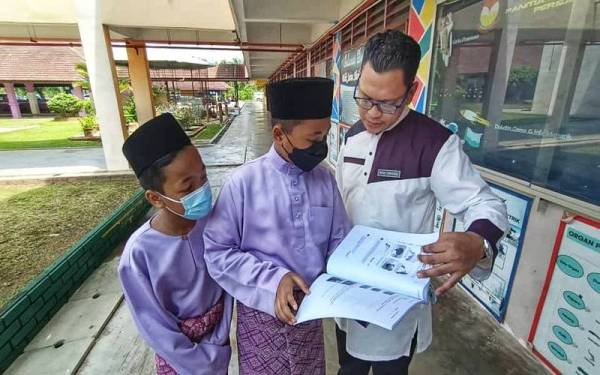 Dua pelajar tahun enam, Mohammad Ammar Rusli (kiri) dan Muhammad kamil Muhammad Sodbir mendapatkan nasihat Mohd Zukhairul mengenai latihan subjek Sains.