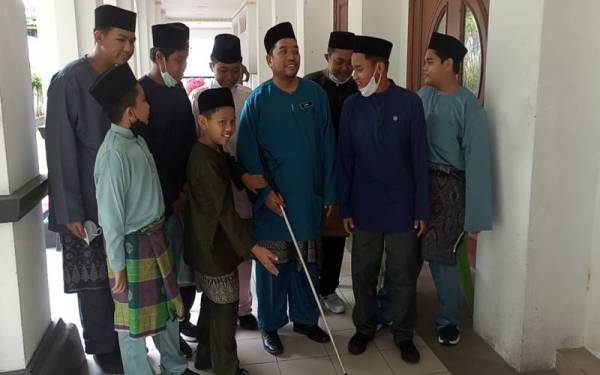 Zamri (tengah) dibantu pelajar sewaktu sambutan Hari Guru di Maktab Sultan Abu Bakar pada Isnin.