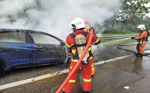 Anggota bomba memadamkan kebakaran sebuah kereta di Kilometer 25.9 Lebuhraya Utara Selatan menghala selatan pada Isnin.