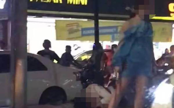 Dalam video itu, kelihatan seorang wanita didapati memegang senjata tajam dipercayai parang dengan terdapat mangsa yang parah terbaring di atas jalan dan berlumuran darah. - Foto ihsan pembaca/media sosial