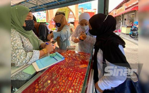 Siti Rohani (kiri) tidak menang tangan melayan pelanggan yang ingin mendapatkan emas dengan harga murah.