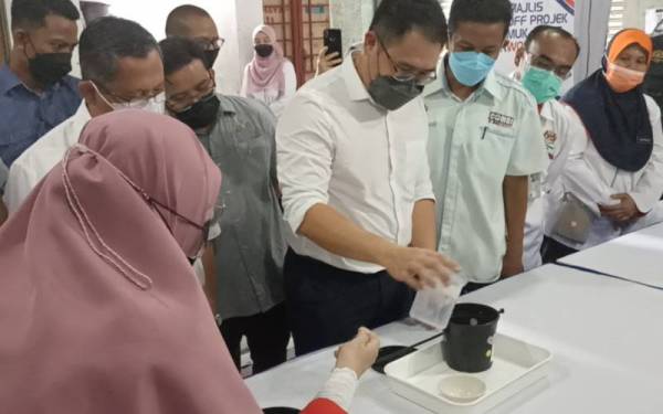 Tian Soon (tengah) melakukan proses melepaskan telur aedes wolbachia ke kawasan lokaliti PPR Kempas pada Rabu.