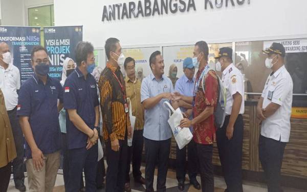 Mohamad Fazli (empat, kiri) menyambut ketibaan penumpang feri dari Tanjung Balai Indonesia sempena hari pertama pembukaan semula Terminal Feri Antarabangsa Kukup, pada Khamis.