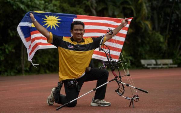 Juwaidi bergambar bersama Jalur Gemilang sebagai meraikan kemenangan selepas berjaya meraih pingat emas menewaskan pemanah Thailand dalam acara akhir Compound Individu Campuran pada Sukan SEA ke-31 di Pusat Latihan Sukan Nasional Hanoi pada Khamis. - Foto Bernama