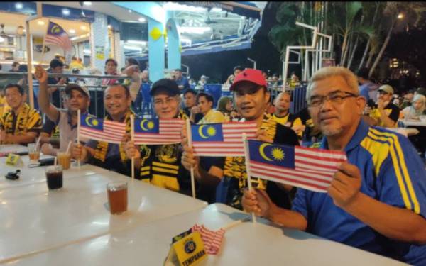 Hashim (kanan) bersama Halimah (tengah) sebelum tayangan perlawanan bola sepak secara langsung bermula di Restoran Hakim Seksyen 7 di sini pada Khamis.