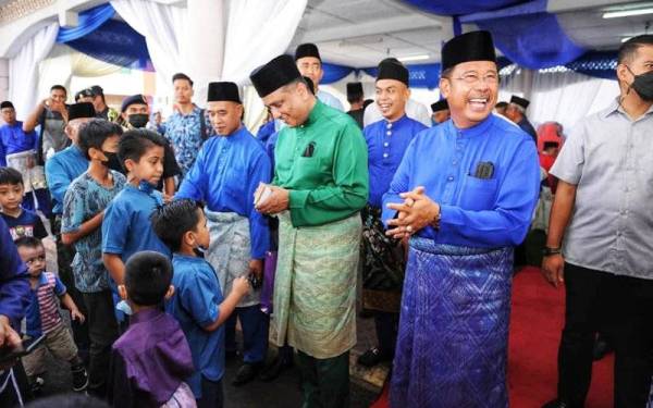 Abdul Rahman (dua dari kanan) bersama Reezal Merican (tiga dari kanan) mengagihkan duit raya kepada kanak-kanak dalam majlis tersebut pada Sabtu.