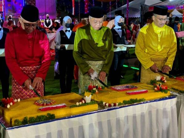 Ismail Sabri (tengah) bersama Hishammuddin (kanan) dan Affendi (kiri) memotong pulut kuning sebagai simbolik upacara sambutan hari raya malam Sabtu.
