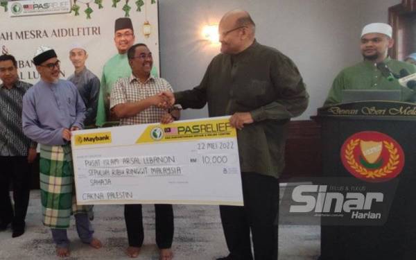 Muhammad Sanusi (tengah) menerima penyerahan ‘mock cheque’ sumbangan daripada NGO kepada PASRelief untuk Projek Pusat Islam Arsal Lubnan pada Majlis Ramah Mesra Aidilfitri dan Penyerahan Sumbangan Projek Pusat Islam Lubnan di Seri Mentaloon, di sini, pada Ahad.