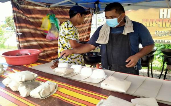 Muhammad Zaidi (kanan) mungkin terpaksa menggantikan ayam dengan ikan bagi nasi kukus yang dijual jika bekalan ayam sukar diperoleh.