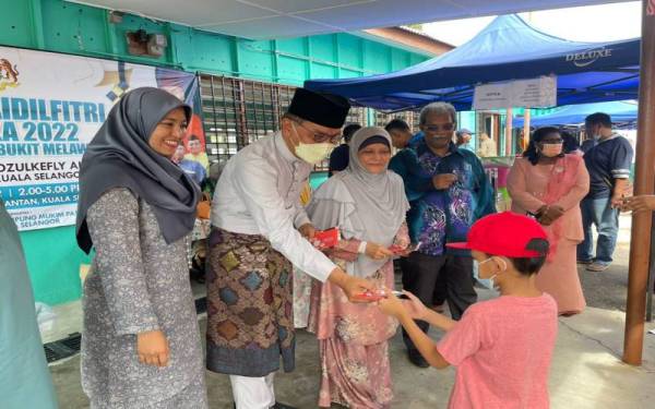 Dzulkefly (dua, kiri) menyampaikan sumbangan duit raya kepada kanak-kanak sempena Majlis Jamuan Terbuka Aidilfitri di Kampung Kuantan, pada petang Ahad.