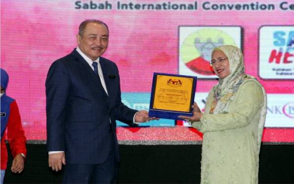 Hajiji menyampaikan hadiah kepada penerima Anugerah Tokoh Guru 2022, Datuk Dr Nuinda Alias (kanan) sempena Majlis Perasmian Sambutan Hari Guru Peringkat Negeri Sabah di Sabah International Convention Centre (SICC), pada Isnin. - Foto Bernama 