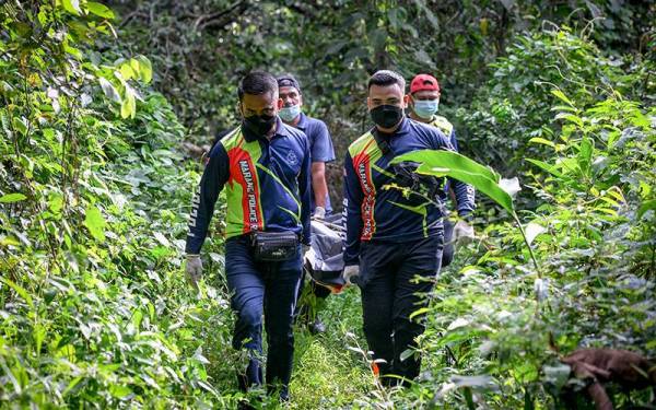 Anggota Unit Forensik PDRM mengangkat mayat Abdul Hadi Ismail, 37, yang dilaporkan hilang pada 13 Mei lepas, selepas ditemukan di kawasan belukar berhampiran Kampung Tanjung Aur pada Selasa. - Foto Bernama