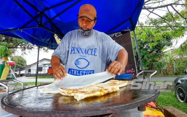 Rohaizan menyediakan roti canai yang ditempah pelanggan.