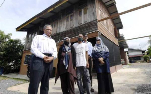 Mustafa (kiri) ketika melawat keluarga miskin tegar di Kampung Kuala Jerlun pada Khamis.