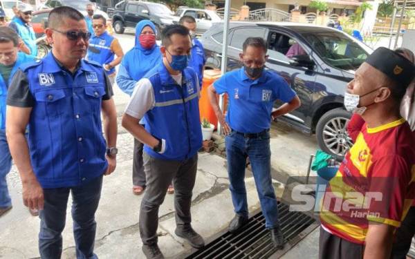 Jamal (kiri) beramah mesra bersama salah seorang penduduk yang terkesan akibat banjir kilat di Sekinchan pada Rabu.