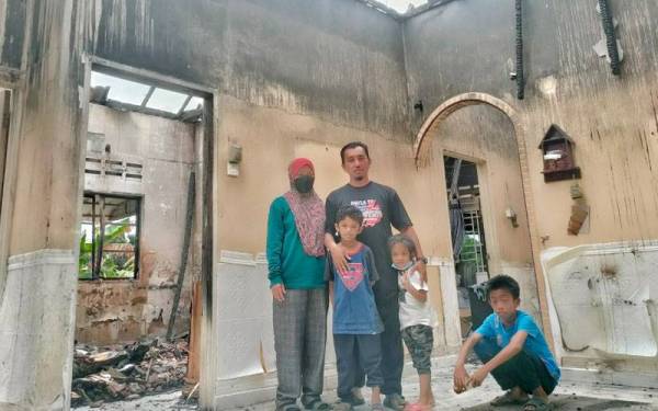 Jasnizah (kiri) bersama keluarganya di rumah mereka yang terbakar pada Ahad lalu.