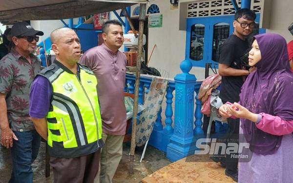 Saarani melawat rumah Che Roha Baharuddin, 53, (kanan) yang terjejas dalam banjir kilat di Felda Trolak Selatan.