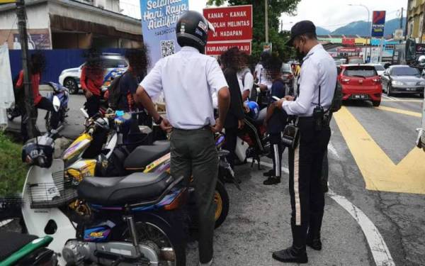 Polis membuat pemeriksaan terhadap pelajar sekolah yang menunggang motosikal